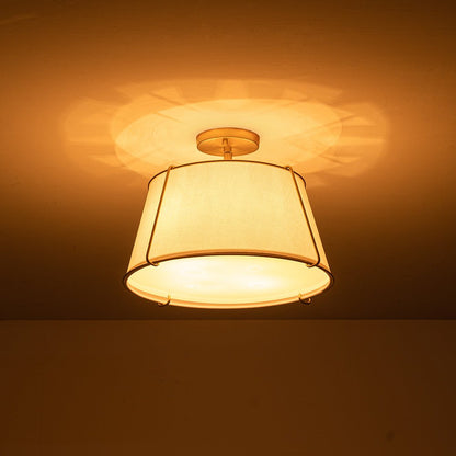 Theodora tapered drum ceiling light – lit from below with a warm glow