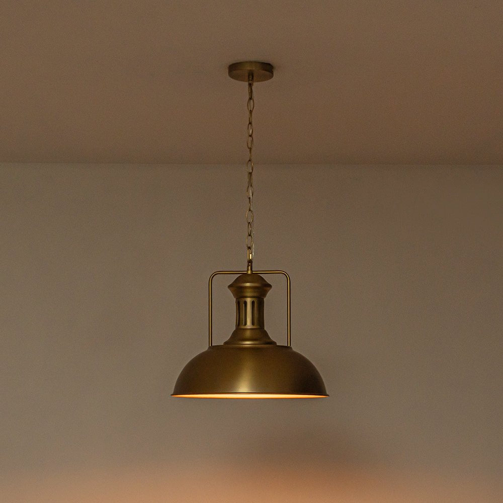 Leopold metal dome pendant light – in gold, lit against a warm wall