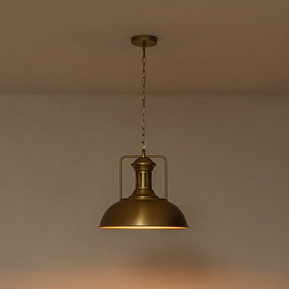 Leopold metal dome pendant light – in gold, lit against a warm wall